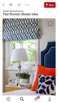 a bedroom with blue and white bedding, orange pillows and a lamp on the nightstand