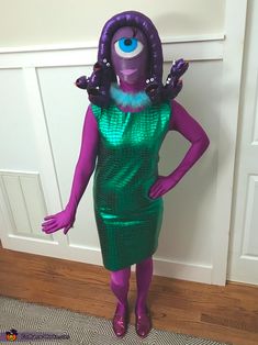 an inflatable purple and green costume stands next to a door