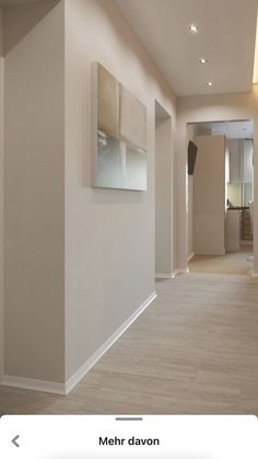 an empty hallway with white walls and wood floors