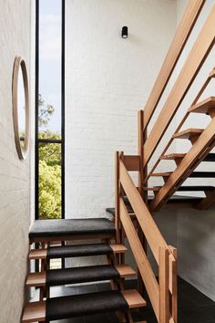 a wooden stair case next to a white brick wall and black tile floor in a house