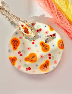 a white plate with fruit designs on it next to a yellow and red feather holder