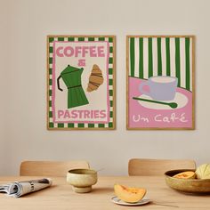 two framed pictures on the wall above a table with fruit and coffee cups in front of them