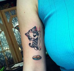 a woman's arm with a cat tattoo on it and a plate of food