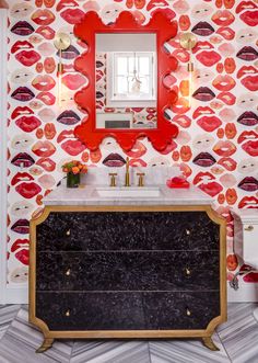 a bathroom decorated in red and pink with lipstick on the wall, mirror above vanity