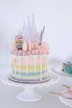 a cake with icing and pastel colors is on a plate next to other desserts