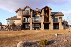 a large stone and wood house in the middle of an open field with rocks on the ground