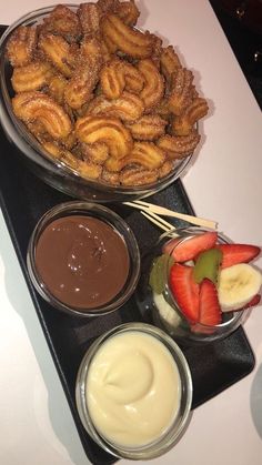 there are many desserts on the table with chocolate sauce and strawberries in bowls