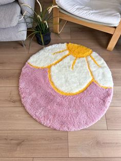 a pink and yellow rug on the floor next to a chair with a plant in it