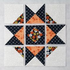 four blocks are arranged in the shape of an orange and black flowered star, one is