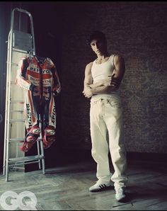 a man standing in front of a motorcycle suit on a rack with his arms crossed