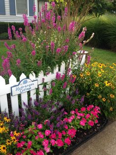 a white picket fence surrounded by colorful flowers