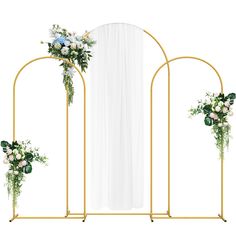 an arch decorated with flowers and greenery stands next to a white curtain in front of it