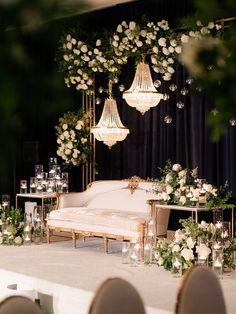 a white couch sitting under chandelier next to a table filled with flowers and candles