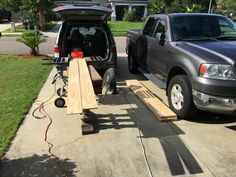 two trucks are parked next to each other in the driveway, one is being worked on