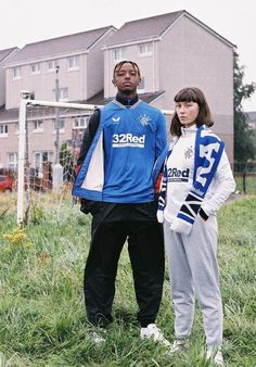 two people standing in front of a soccer ball on a field with houses behind them