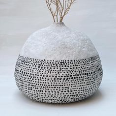 a black and white vase with branches sticking out of it