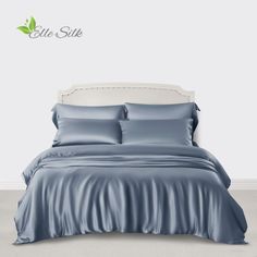 a bed with blue sheets and pillows on top of it in a white walled room