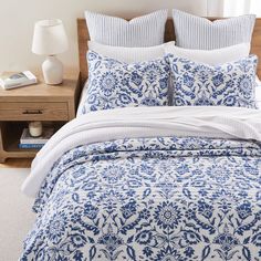 a bed with blue and white comforter in a bedroom next to a night stand