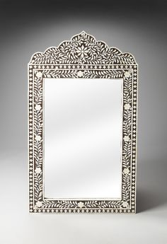 an ornate silver mirror on a grey background with light reflection in the middle and back