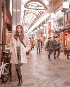 a woman standing next to a bike on a sidewalk in front of shops and people