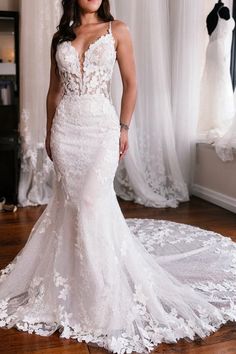 a woman in a white wedding dress standing on a wooden floor next to a window