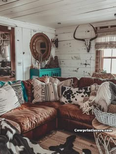 a living room filled with lots of furniture and pillows on top of brown leather couches