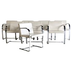 six white leather chairs with chrome legs and armrests, all facing different directions