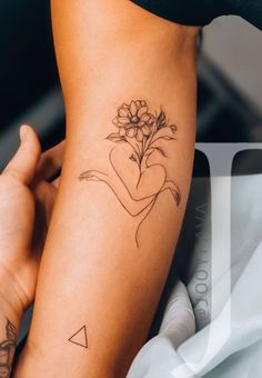 a woman's arm with a flower tattoo on it and a triangle in the middle