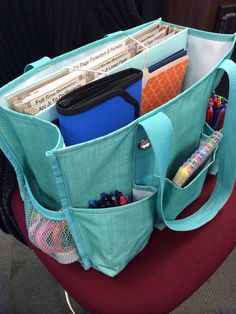 an open bag sitting on top of a chair filled with books and other items in it