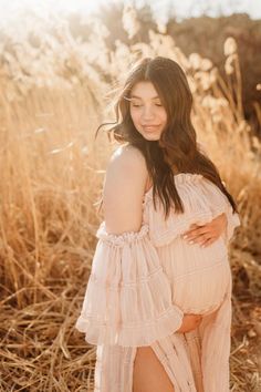 a pregnant woman poses for a photo in a field