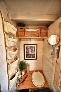 a small bathroom with a toilet, sink and hanging baskets