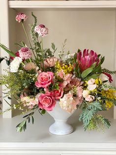 a white vase filled with lots of different colored flowers