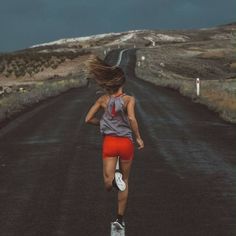 a woman running down a road in the middle of nowhere