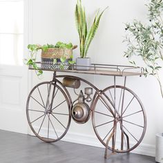 an old fashioned bicycle with potted plants on the top and bottom shelf, in front of a white wall