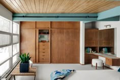 a living room filled with lots of furniture and wooden cabinets next to a large window