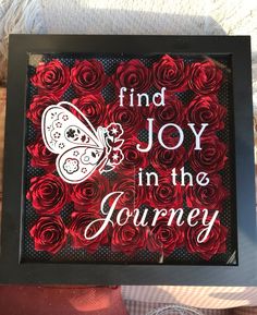 a black frame with red roses and a butterfly on it that says find joy in the journey