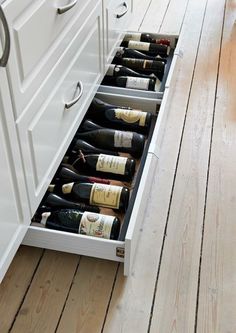 an open drawer with several bottles of wine in it