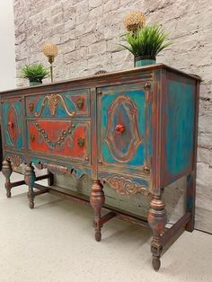 an old dresser with two potted plants sitting on it's top and bottom