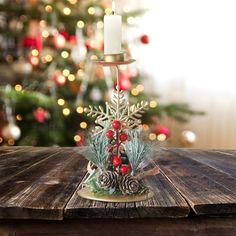 a wooden table topped with a candle and a christmas tree in the backround