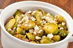 a white bowl filled with brussel sprouts and feta cheese