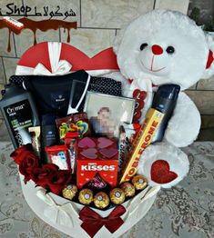 a white teddy bear sitting next to a valentine's day gift basket filled with chocolates and candy