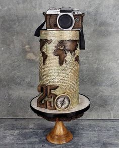 an old fashioned camera on top of a cake with the world in it's center