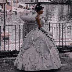 a woman in a ball gown is standing by the water