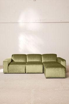 a large green couch sitting on top of a white floor next to a lamp shade