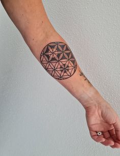 a person's arm with a tattoo on it and geometric shapes in the background