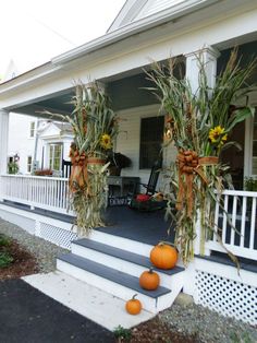 two pumpkins sitting on the front steps of a house with sunflowers hanging from them