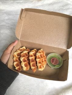 a person holding a box with waffles in it