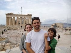 two women and a man standing in front of the parthenion, with an ancient building in the background