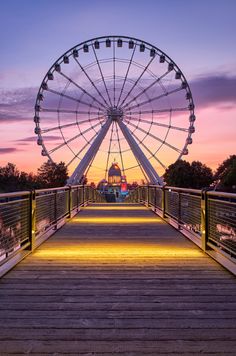 a large ferris wheel sitting on top of a wooden bridge