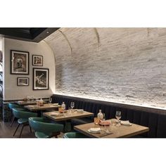 an empty restaurant with tables and chairs in front of a stone wall that has pictures on it